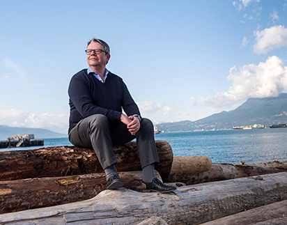 Dr. Michael Kobor sitting on logs at Spanish Banks beach